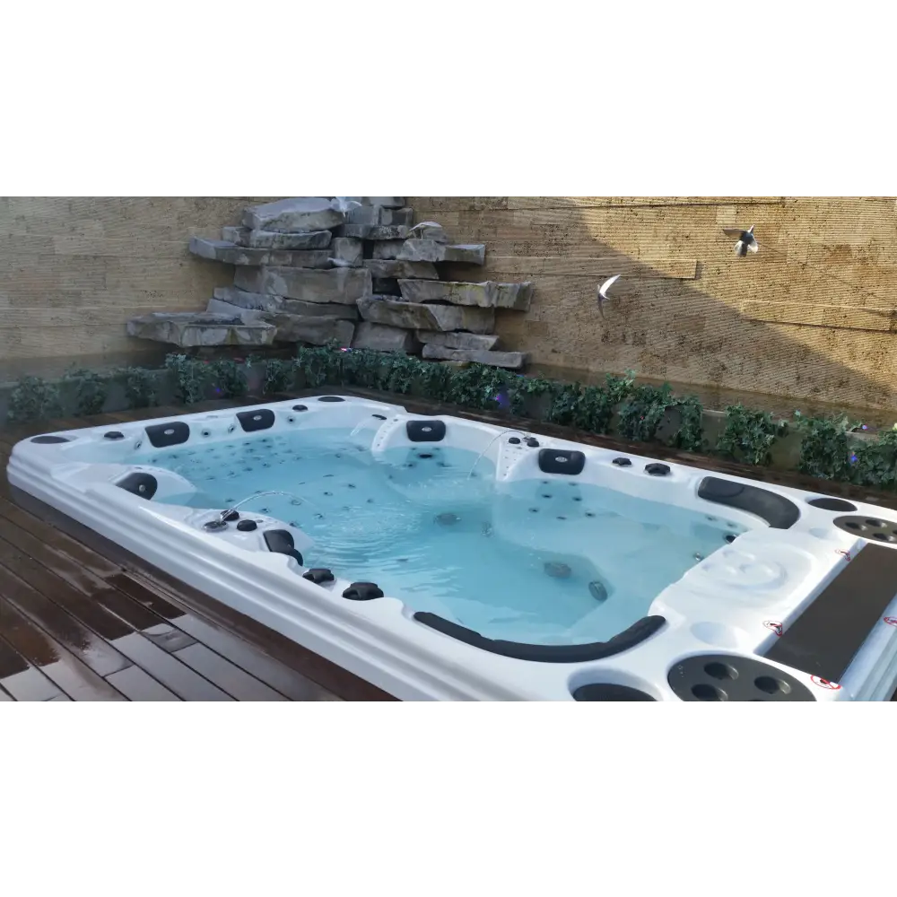 Vitvitt spabad PassionSpa Theater Spabad med svarta säten och jetmunstycken mot stenval